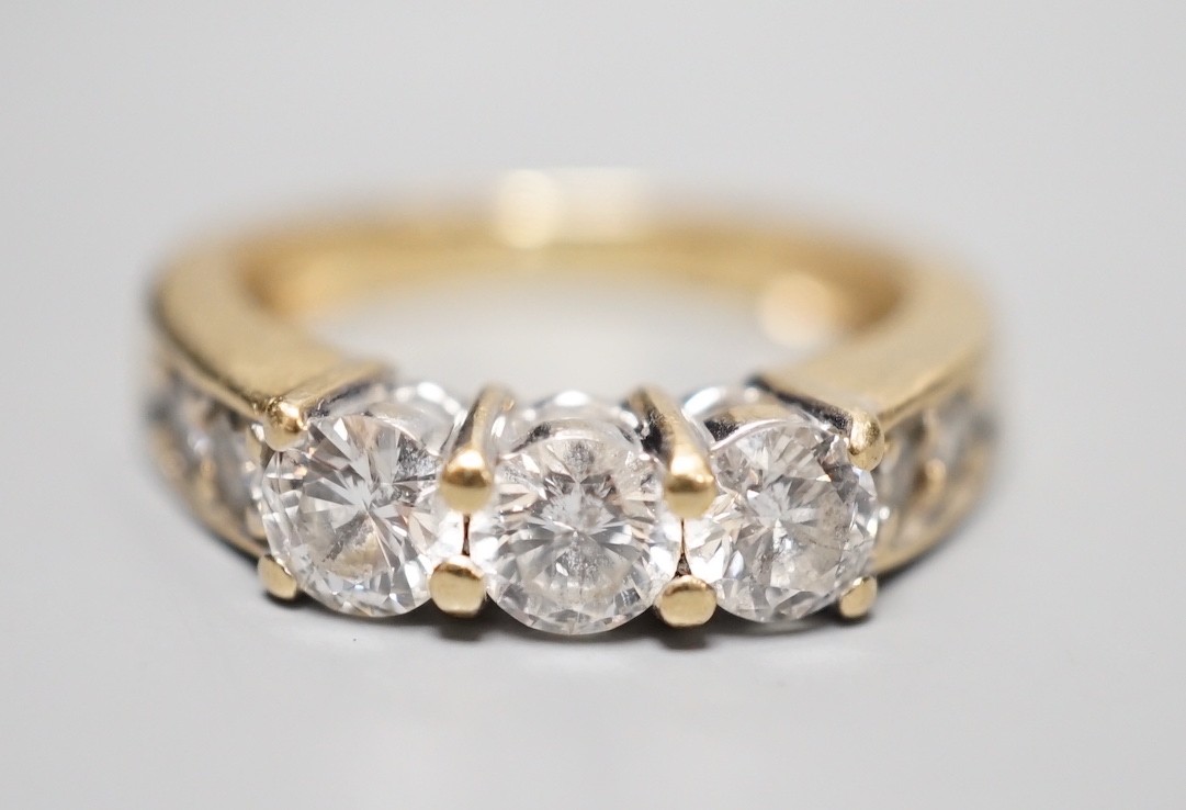 A 14k yellow metal and three stone diamond ring, with four stone diamond set shoulders, size K, gross weight 4.3 grams